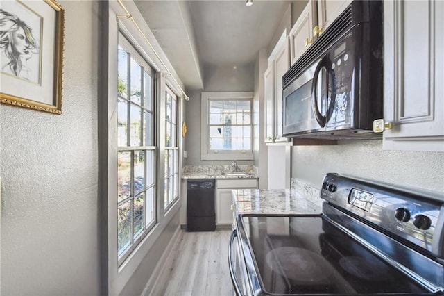 2512 Magazine St Unit D, New Orleans, LA 70130 - kitchen featuring black appliances, light wood-style floors, a textured wall, light stone counters, and white cabinets