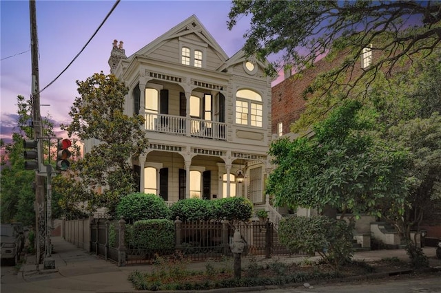 639 Esplanade Ave, New Orleans, LA 70116 - victorian home featuring a balcony, a fenced front yard, covered porch, and a chimney