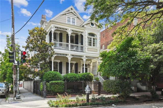 639 Esplanade Ave, New Orleans, LA 70116 - victorian house with a balcony, covered porch, a fenced front yard, and a chimney