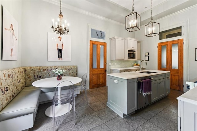 639 Esplanade Ave, New Orleans, LA 70116 - kitchen featuring a chandelier, appliances with stainless steel finishes, light countertops, ornamental molding, and an island with sink