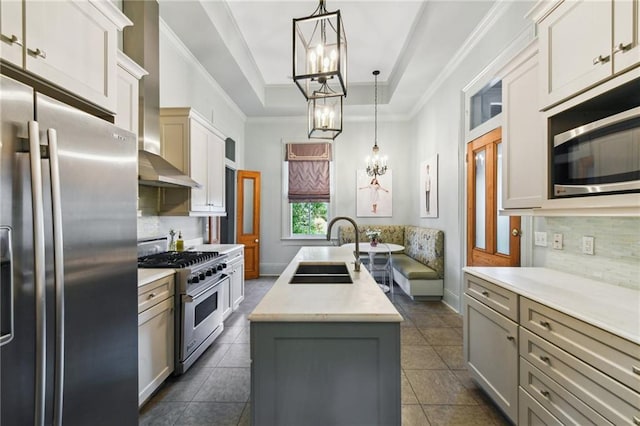 639 Esplanade Ave, New Orleans, LA 70116 - kitchen with appliances with stainless steel finishes, an island with sink, light countertops, tasteful backsplash, and a raised ceiling