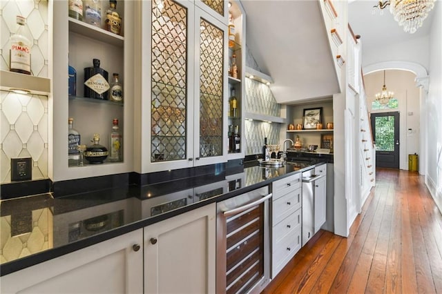 639 Esplanade Ave, New Orleans, LA 70116 - bar featuring beverage cooler, a chandelier, arched walkways, dark wood-style floors, and lofted ceiling