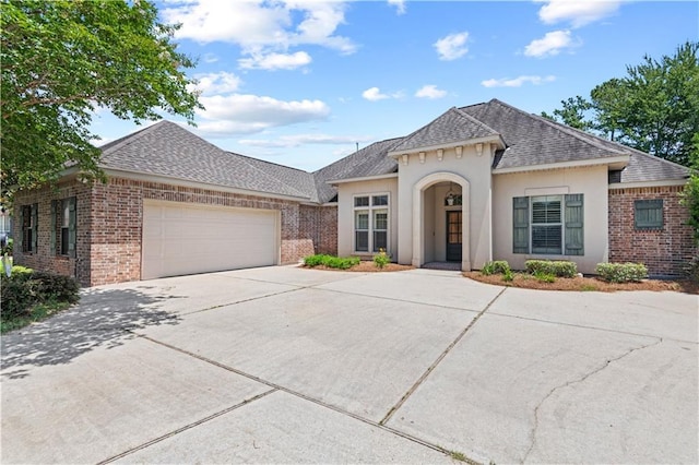 1521 Rue De Fontaine, Covington, LA 70433 - view of front of house featuring roof with shingles, brick siding, and an attached garage