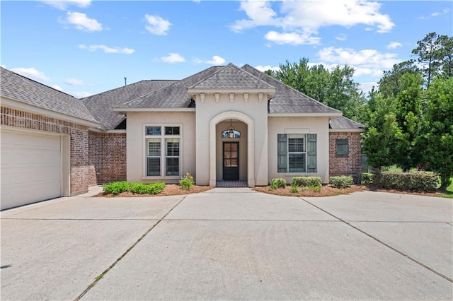 1521 Rue De Fontaine, Covington, LA 70433 - view of front of property featuring concrete driveway, roof with shingles, brick siding, and stucco siding