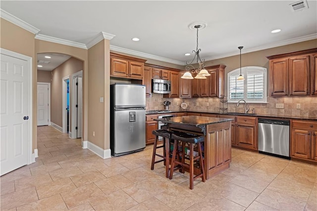 1521 Rue De Fontaine, Covington, LA 70433 - kitchen with stainless steel appliances, brown cabinetry, arched walkways, a breakfast bar area, and tasteful backsplash