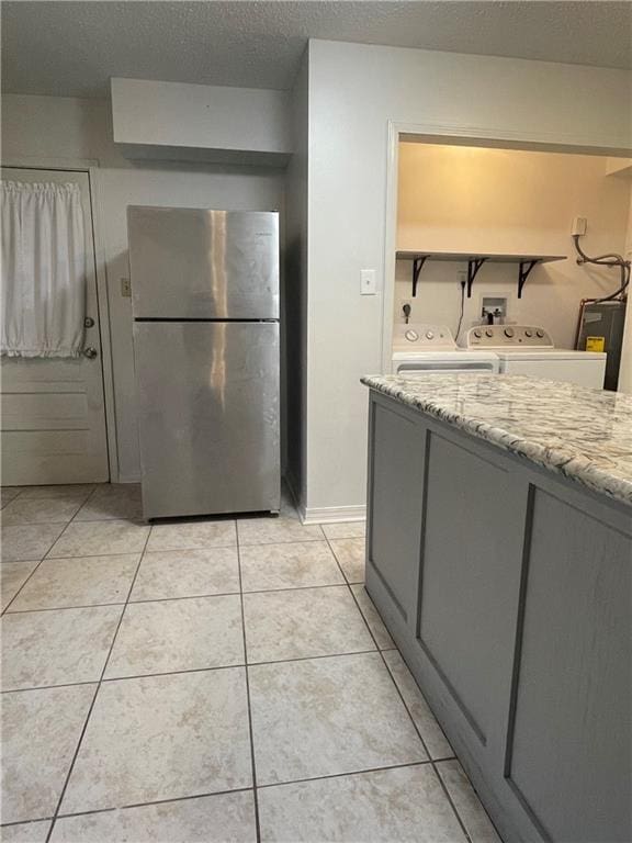 51 Brandon Hall Dr, Destrehan, LA 70047 - kitchen with freestanding refrigerator, gray cabinetry, washer and dryer, a textured ceiling, and light tile patterned floors