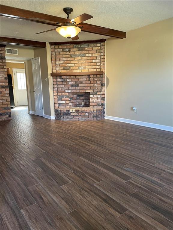 51 Brandon Hall Dr, Destrehan, LA 70047 - unfurnished living room featuring a ceiling fan, beam ceiling, dark wood-style floors, a textured ceiling, and a brick fireplace