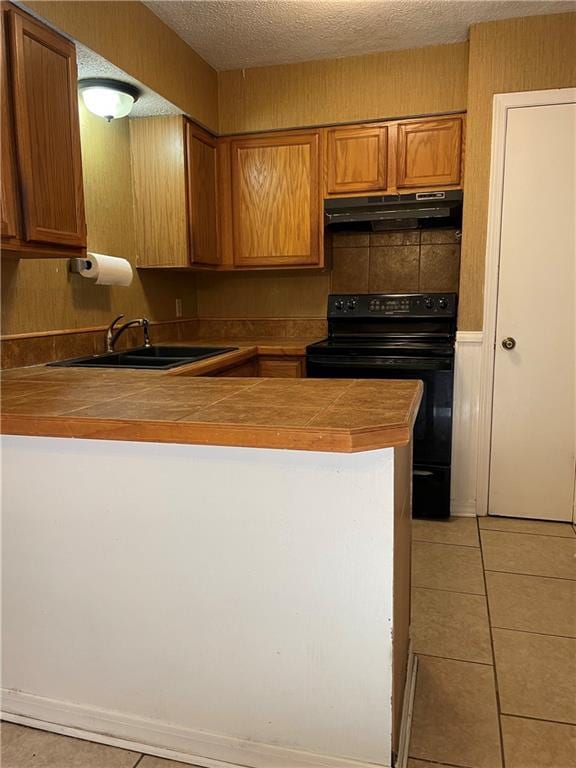 51 Brandon Hall Dr, Destrehan, LA 70047 - kitchen featuring black range with electric stovetop, extractor fan, a peninsula, light tile patterned floors, and brown cabinets