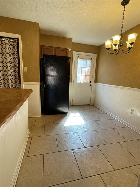 51 Brandon Hall Dr, Destrehan, LA 70047 - entryway featuring a wainscoted wall, a chandelier, a textured ceiling, and light tile patterned floors
