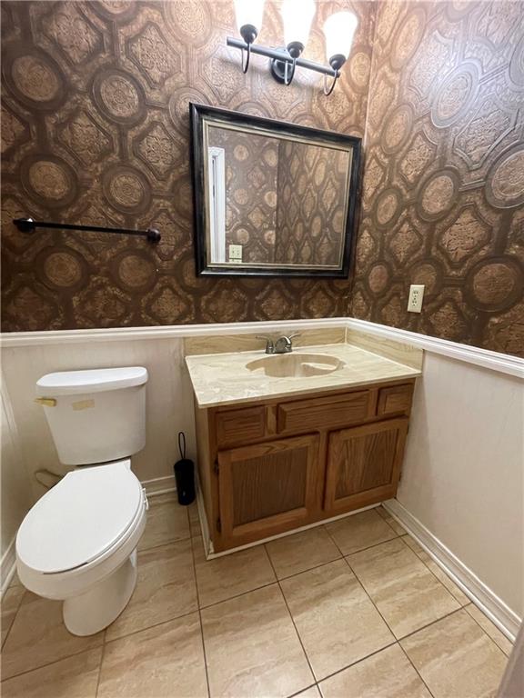 51 Brandon Hall Dr, Destrehan, LA 70047 - half bath with wallpapered walls, a wainscoted wall, vanity, and tile patterned flooring