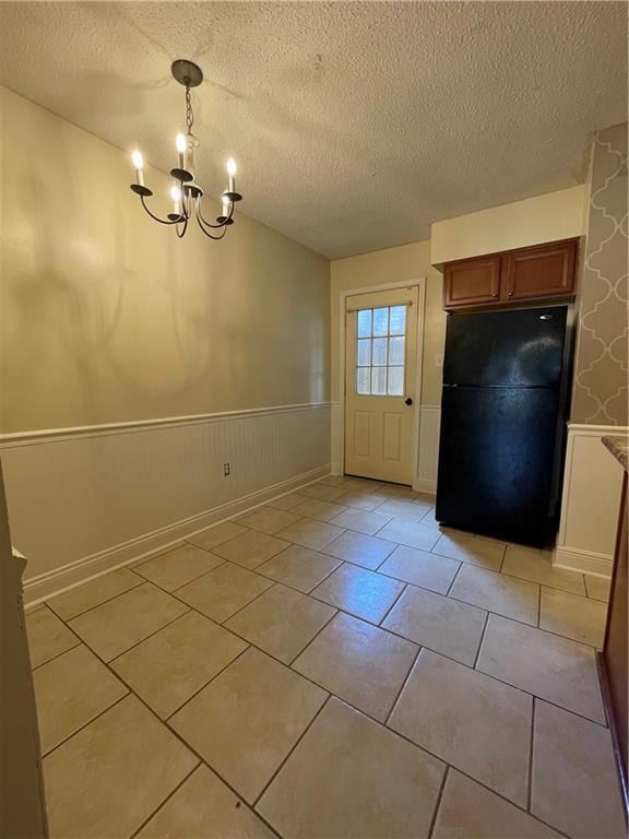 51 Brandon Hall Dr, Destrehan, LA 70047 - unfurnished dining area with a textured ceiling, a wainscoted wall, a chandelier, and light tile patterned flooring