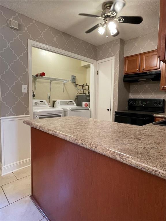 51 Brandon Hall Dr, Destrehan, LA 70047 - kitchen featuring black electric range oven, under cabinet range hood, separate washer and dryer, wallpapered walls, and ceiling fan