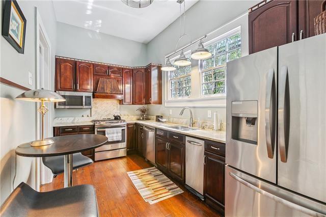 400 Millaudon St, New Orleans, LA 70118 - kitchen featuring appliances with stainless steel finishes, premium range hood, light countertops, dark wood finished floors, and decorative light fixtures