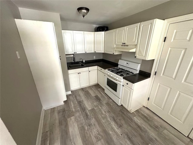 3046 Slidell Ave, Slidell, LA 70458 - kitchen featuring white gas range oven, under cabinet range hood, dark countertops, dark wood-style flooring, and white cabinetry
