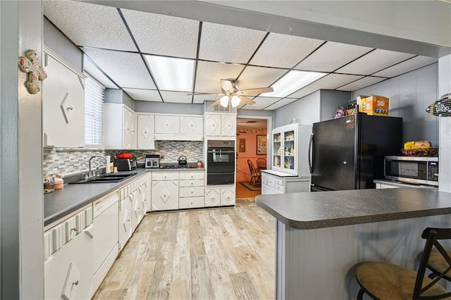 5225 Conti St, New Orleans, LA 70124 - kitchen featuring black appliances, a warming drawer, light wood-type flooring, dark countertops, and a drop ceiling