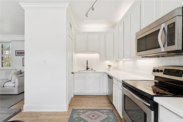 1783 Coliseum St Unit H, New Orleans, LA 70130 - kitchen with stainless steel appliances, white cabinetry, tasteful backsplash, light wood-type flooring, and crown molding