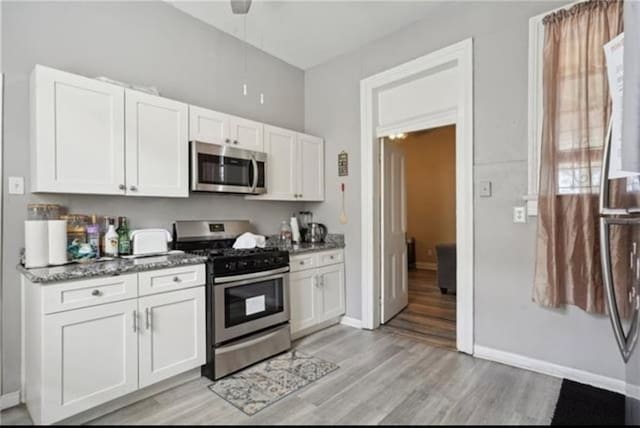 3026 Short St, New Orleans, LA 70125 - kitchen featuring stainless steel appliances, light wood-style floors, white cabinets, and dark stone countertops