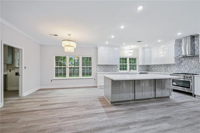 325 Jasmine Dr, Mandeville, LA 70471 - kitchen with wall chimney exhaust hood, high end range, light countertops, plenty of natural light, and ornamental molding