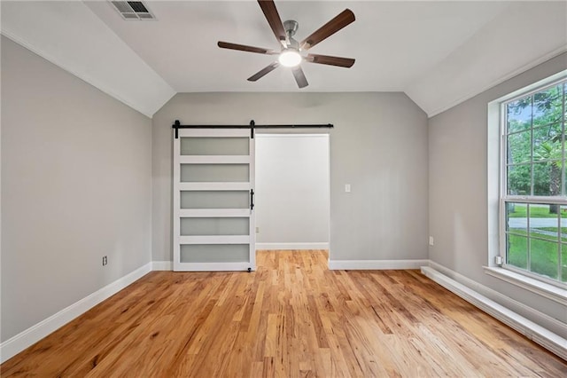 325 Jasmine Dr, Mandeville, LA 70471 - unfurnished bedroom with vaulted ceiling, a barn door, light wood-style flooring, and ceiling fan