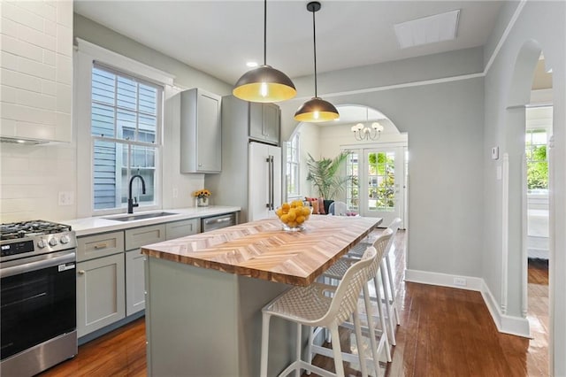 2303 Wisteria St, New Orleans, LA 70122 - kitchen with appliances with stainless steel finishes, gray cabinets, wood counters, dark wood-style floors, and healthy amount of natural light