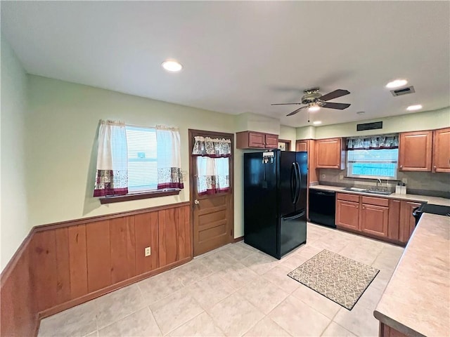 6012 Bridget St, Metairie, LA 70003 - kitchen with black appliances, healthy amount of natural light, light tile patterned flooring, light countertops, and a wainscoted wall