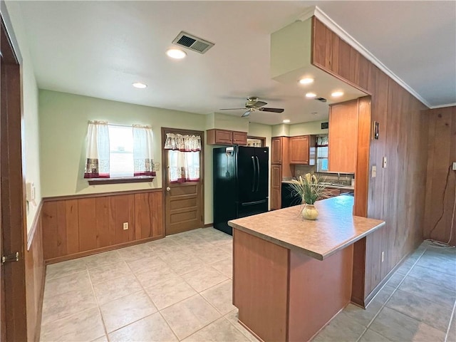 6012 Bridget St, Metairie, LA 70003 - kitchen with freestanding refrigerator, wood walls, healthy amount of natural light, brown cabinets, and a peninsula