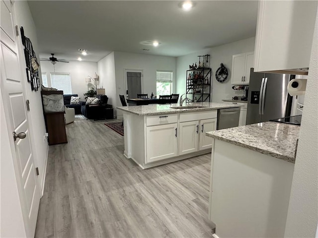 42423 Landing View Rd, Ponchatoula, LA 70454 - kitchen with stainless steel appliances, white cabinetry, a center island with sink, light wood-style floors, and light stone countertops