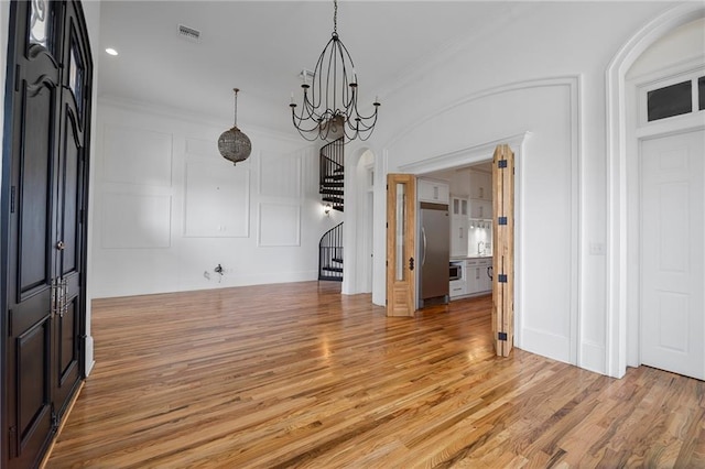 6978 Canal Blvd, New Orleans, LA 70124 - unfurnished dining area with stairway, light wood-style floors, a decorative wall, ornamental molding, and a chandelier