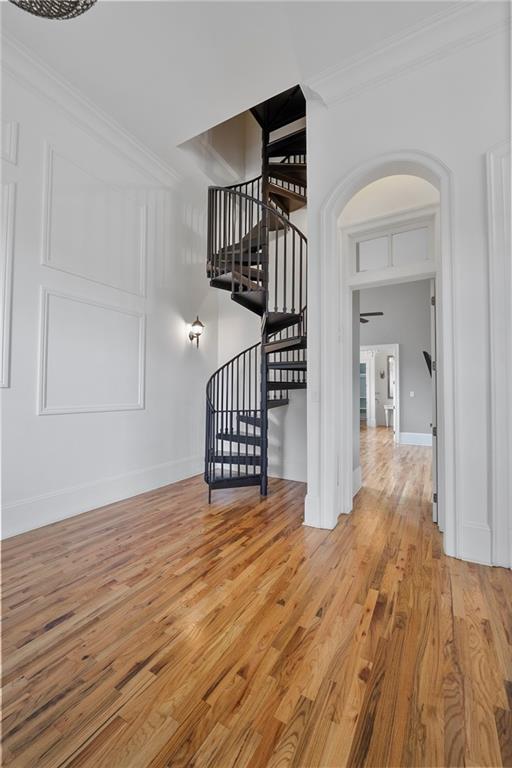 6978 Canal Blvd, New Orleans, LA 70124 - unfurnished living room with ornamental molding, wood finished floors, stairway, and arched walkways