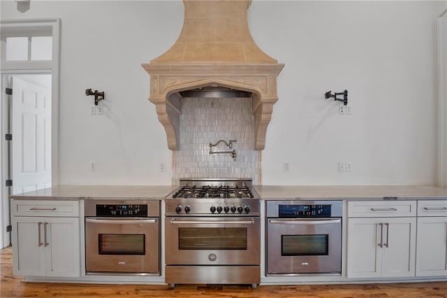 6978 Canal Blvd, New Orleans, LA 70124 - kitchen featuring appliances with stainless steel finishes, tasteful backsplash, light stone countertops, and light wood-style flooring
