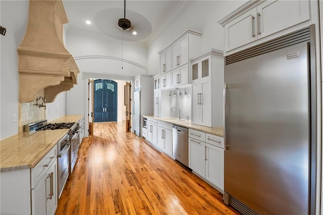 6978 Canal Blvd, New Orleans, LA 70124 - kitchen featuring appliances with stainless steel finishes, light countertops, premium range hood, tasteful backsplash, and light wood finished floors