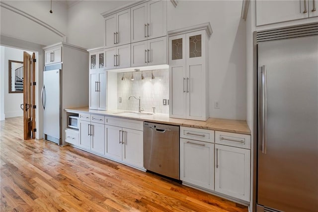 6978 Canal Blvd, New Orleans, LA 70124 - kitchen with built in appliances, backsplash, light wood finished floors, glass insert cabinets, and light stone counters