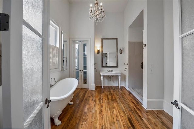 6978 Canal Blvd, New Orleans, LA 70124 - bathroom featuring a chandelier, wood finished floors, a freestanding tub, and french doors