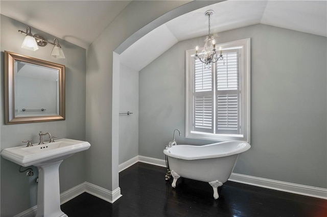 6978 Canal Blvd, New Orleans, LA 70124 - bathroom with lofted ceiling, a soaking tub, a chandelier, and wood finished floors