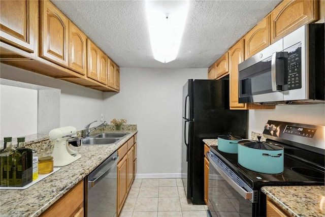 10286 W Winston Ave Unit 15, Baton Rouge, LA 70809 - kitchen featuring appliances with stainless steel finishes, a textured ceiling, light stone counters, light tile patterned floors, and brown cabinets