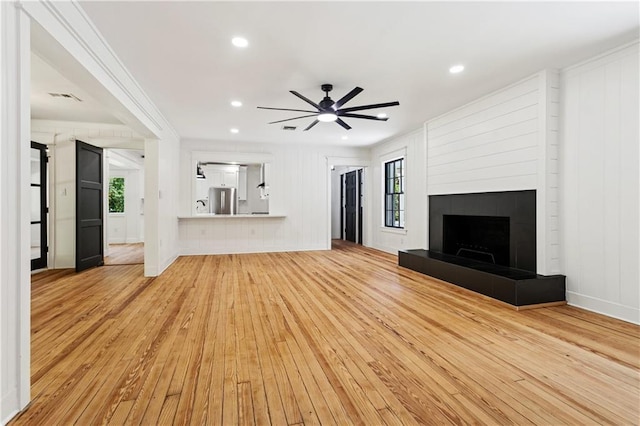 72287 Military Rd, Covington, LA 70435 - unfurnished living room with light wood-style floors, crown molding, ceiling fan, a tiled fireplace, and recessed lighting