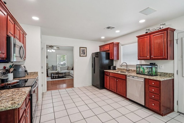 70105 10th St, Covington, LA 70433 - kitchen featuring appliances with stainless steel finishes, dark brown cabinets, ceiling fan, light tile patterned flooring, and light stone counters