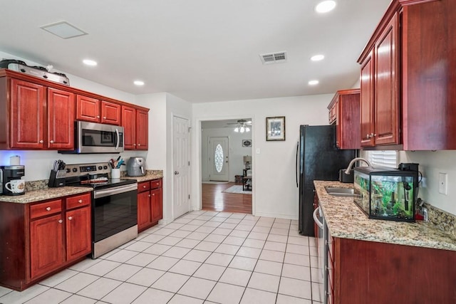70105 10th St, Covington, LA 70433 - kitchen featuring appliances with stainless steel finishes, reddish brown cabinets, a ceiling fan, recessed lighting, and light tile patterned floors