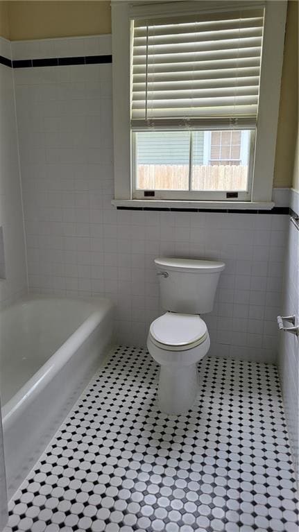 177375 N Dorgenois St, New Orleans, LA 70119 - bathroom with tile walls, a tub, a wainscoted wall, and tile patterned flooring