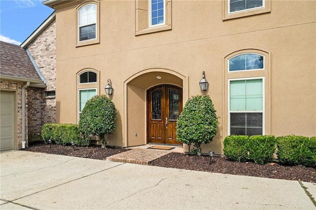 412 Aspen Ln, Covington, LA 70433 - view of exterior entry featuring stucco siding, concrete driveway, and an attached garage
