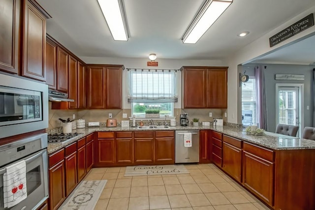 784 Lakeview Ln, Covington, LA 70435 - kitchen featuring appliances with stainless steel finishes, a peninsula, light stone countertops, light tile patterned flooring, and under cabinet range hood
