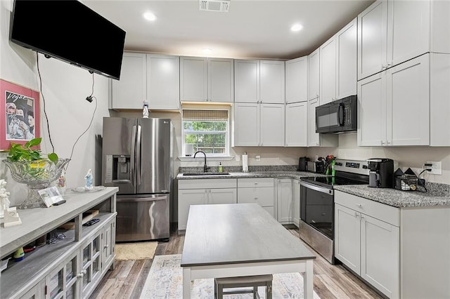 540 N 8th St, Ponchatoula, LA 70454 - kitchen with appliances with stainless steel finishes, light wood finished floors, light stone counters, white cabinets, and recessed lighting