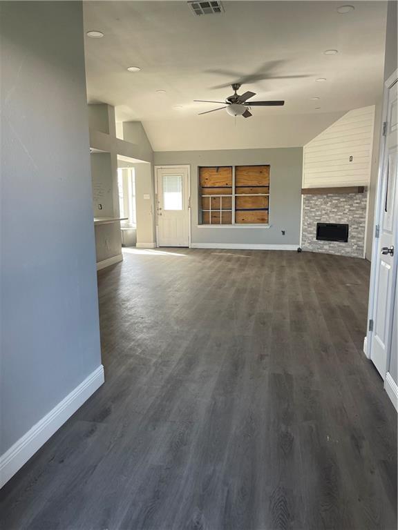 40 Cane Dr, La Place, LA 70068 - unfurnished living room with lofted ceiling, ceiling fan, a stone fireplace, and dark wood-type flooring