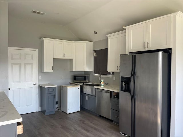 40 Cane Dr, La Place, LA 70068 - kitchen with appliances with stainless steel finishes, lofted ceiling, dark wood-style floors, white cabinets, and light stone counters