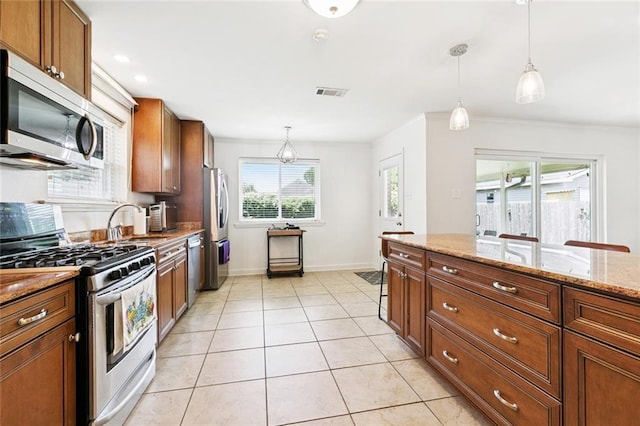 3514 Bore St, Metairie, LA 70001 - kitchen with stainless steel appliances, hanging light fixtures, brown cabinets, light stone counters, and light tile patterned floors