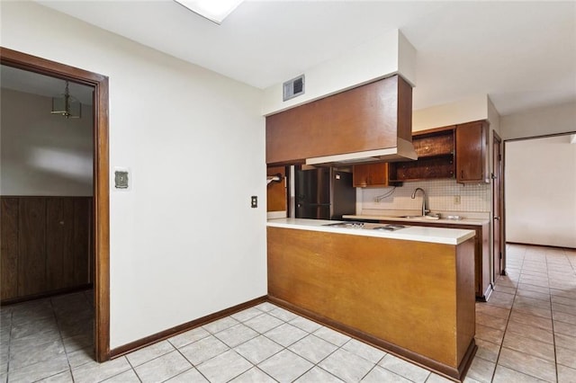 2608 Hyman Pl, New Orleans, LA 70131 - kitchen featuring freestanding refrigerator, backsplash, light countertops, a peninsula, and light tile patterned floors