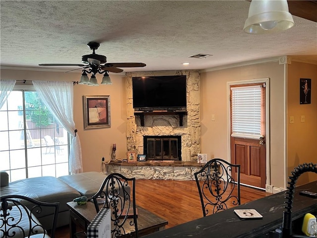 3821 Derbigny St, Metairie, LA 70001 - living area with ornamental molding, ceiling fan, a textured ceiling, wood finished floors, and a stone fireplace