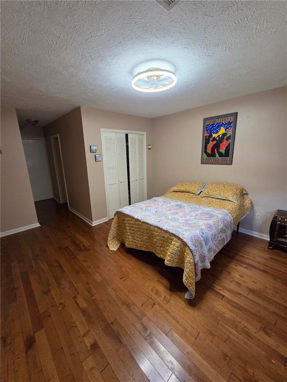 3821 Derbigny St, Metairie, LA 70001 - bedroom featuring wood-type flooring, a textured ceiling, and a closet