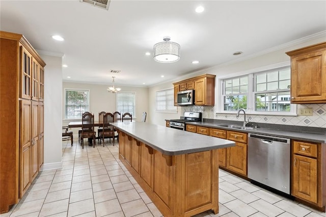4827 Utica St, Metairie, LA 70006 - kitchen featuring appliances with stainless steel finishes, a center island, decorative backsplash, brown cabinetry, and recessed lighting