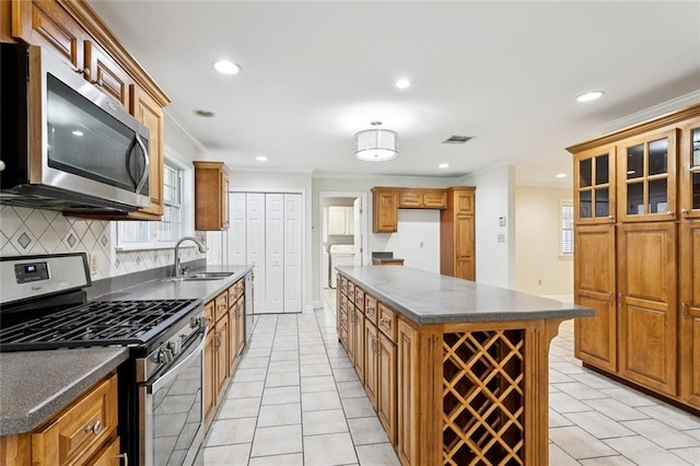 4827 Utica St, Metairie, LA 70006 - kitchen featuring stainless steel appliances, separate washer and dryer, dark countertops, crown molding, and backsplash